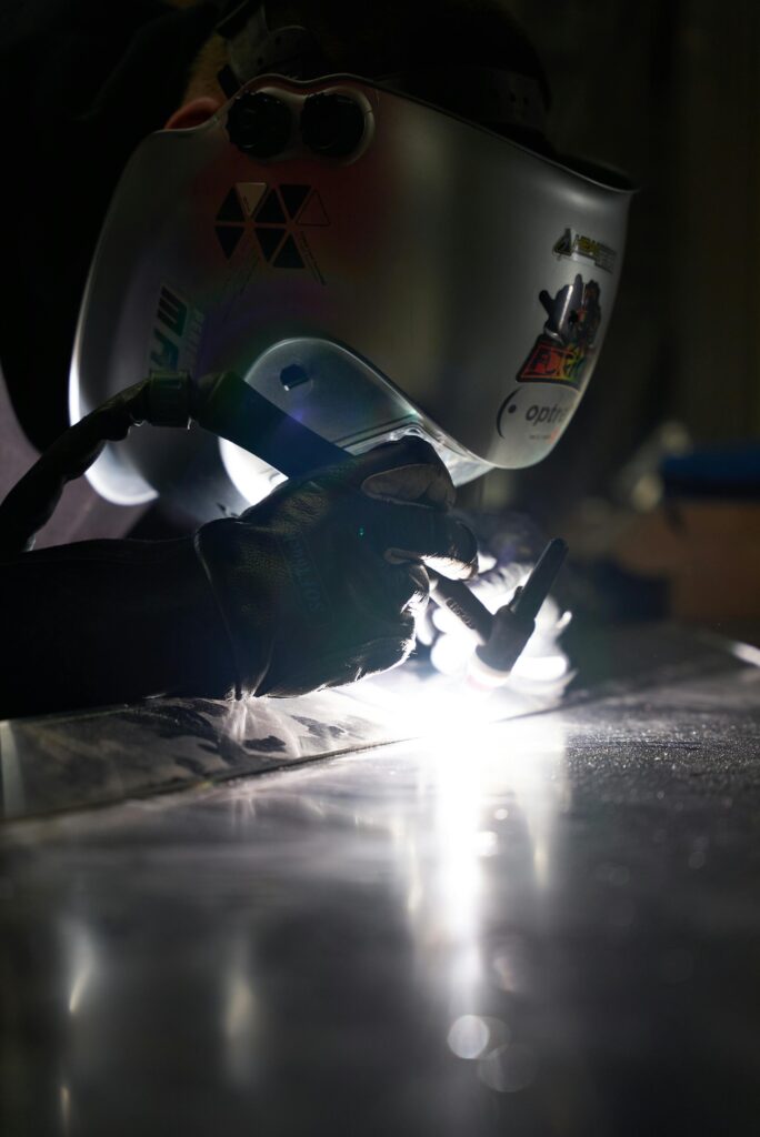 pexels photo 9130186 9130186 Close-up of a welder in action, wearing protective gear and welding metal indoors.